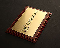 złoty grawerowany szyld firmowy tablica reklamowa na ozdobnym drewniany podkładzie dla firmy Omegam
