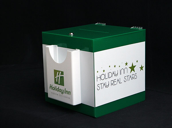 Pojemnik na opinie klientów hotelu wykonany z zielonej pleksi z kieszonką na ankiety